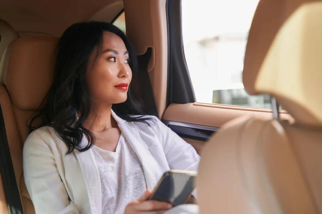 Charming woman in a car looking away thoughtfully while sitting in the driver’s seat.