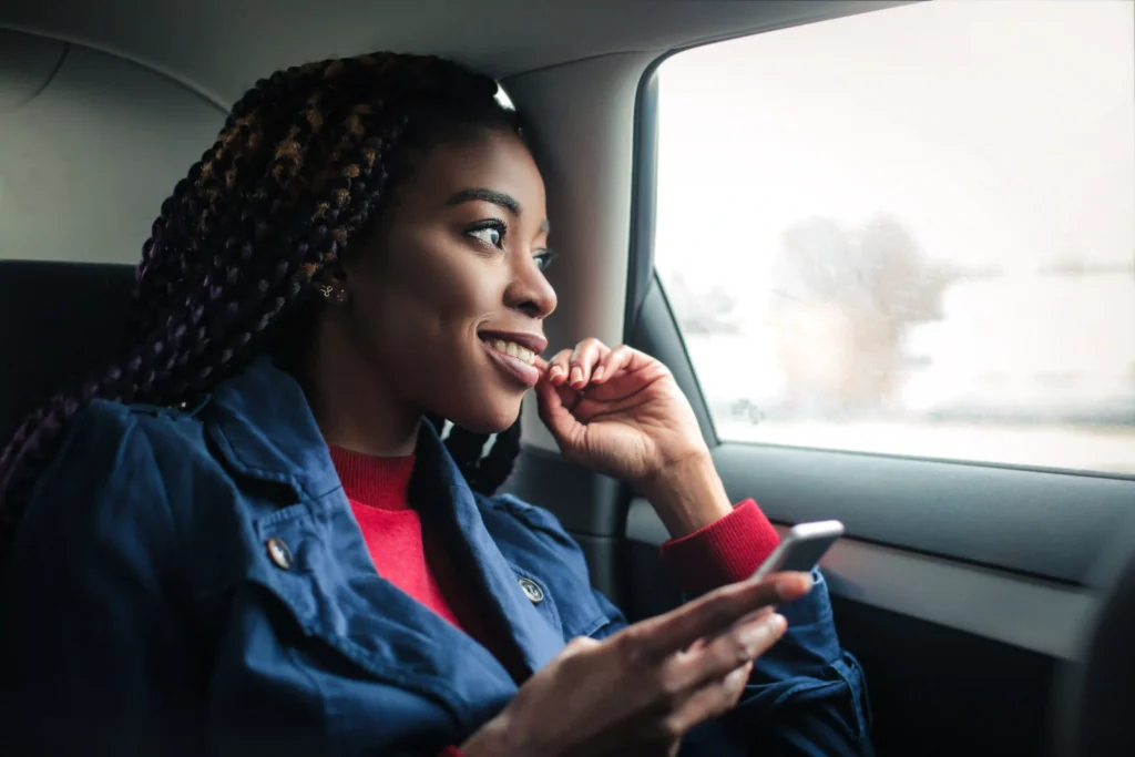 Happy Black girl sitting in a car, smiling and looking out of the window.